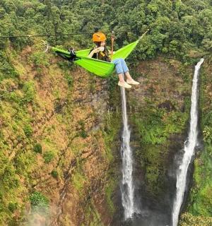 a man in a hammock next to a waterfall
