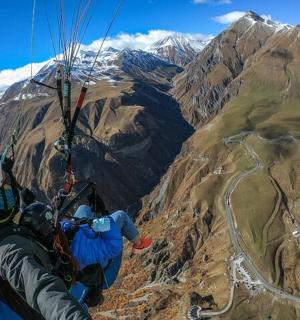 two people are flying in a parachute over a mountain