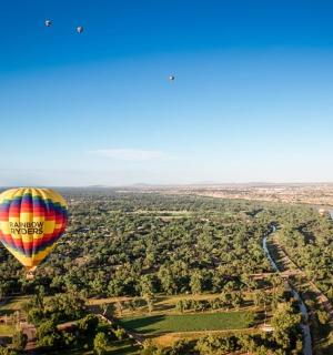 a colorful hot air balloon flying over a river