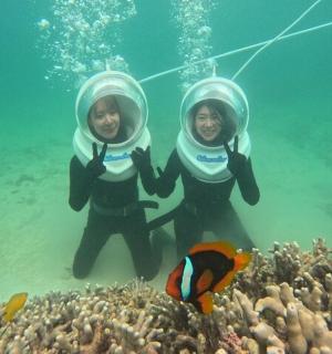 two people are standing in the water near a reef