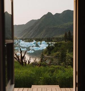a view from a door of a river with mountains