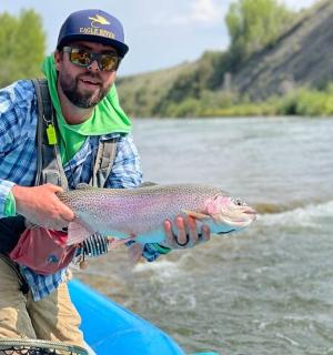 一名男子在河上的船上拿着一条鱼