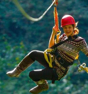 a woman hanging from a rope on a zip line