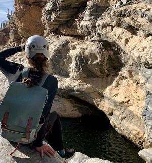 žena sedí na skále s helmou