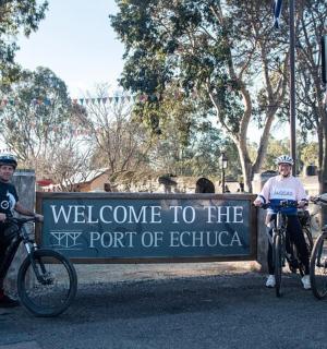 三个人骑着自行车站在标志牌前