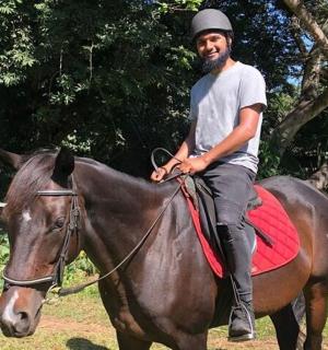 一名男子骑在一匹棕色的马上