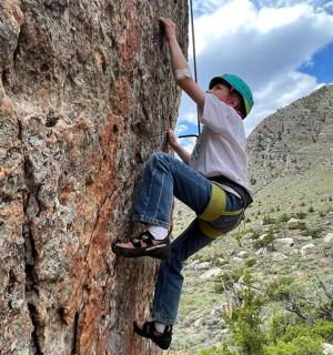 mladý chlapec leze po skalní stěně