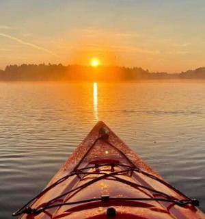 eine Person in einem Kajak auf einem See bei Sonnenuntergang