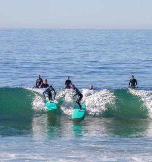 skupina lidí jedoucích na vlně na surfových prknech v oceánu