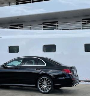 一辆黑色轿车停在一艘大船旁边