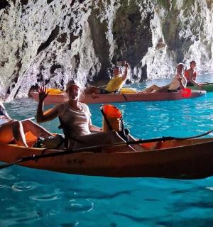 eine Gruppe von Menschen, die im Wasser in der Nähe einer Höhle Kajak fahren