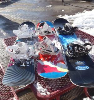 Tři snowboardy sedící na piknikovém stole ve sněhu