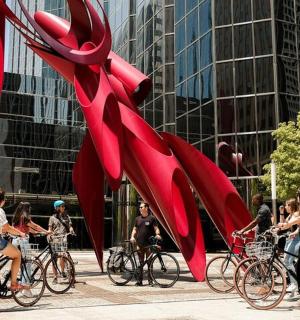 a group of people riding bikes next to a red lobster sculpture