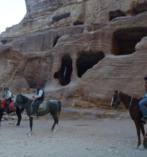 skupina lidí jezdících na koních v poušti