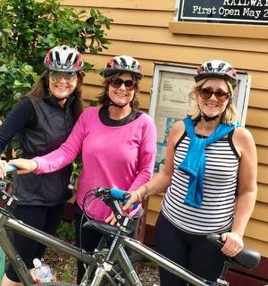 三位戴着头盔的女士站在自行车旁边
