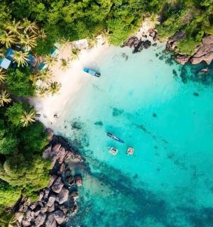 an aerial view of a beach with boats in the water