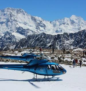 a blue helicopter parked on top of a snow covered mountain