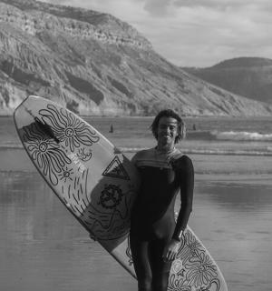 a woman standing on the beach holding a surfboard