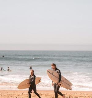 two people walking on the beach with their surfboards