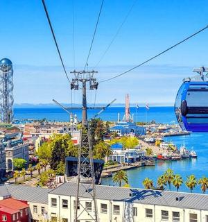 a gondola flying over a city with the ocean