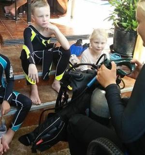 a woman taking a picture of two children on a motor bike