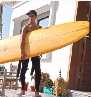 a man holding a surfboard in front of a house