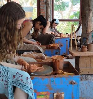 eine Gruppe von Frauen, die um einen Tisch sitzen und Töpfern