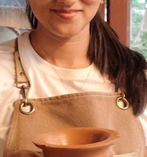 eine Frau in einer Schürze hält eine Tonschale