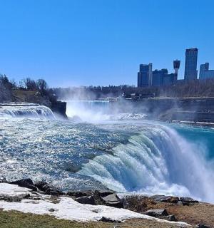 a waterfall in a river with a city in the background