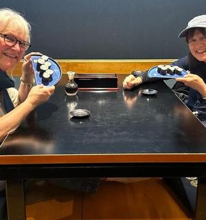 两位老年妇女坐在桌旁,手里拿着盘子