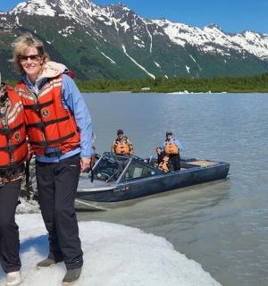 a man and woman standing next to a boat on a lake