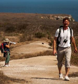 a man walking down a dirt road with a backpack