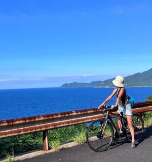 a woman standing next to a bike on a road