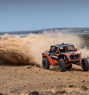 an orange monster truck driving in the dirt