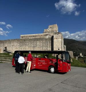 skupina lidí stojících před červeným autobusem