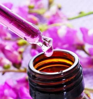 a close up of a bottle of essential oil with pink flowers