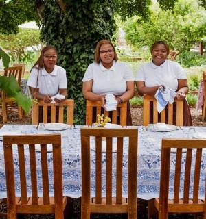 三个女人坐在桌旁,桌上有一只鸟