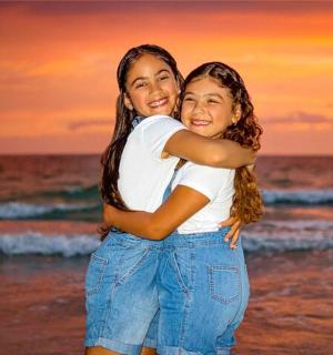 日落时分,两个女孩在沙滩上拥抱