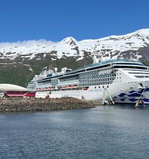 a cruise ship docked at a dock with a snow covered mountain