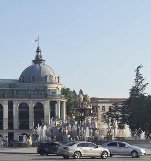 a building with cars parked in front of a fountain