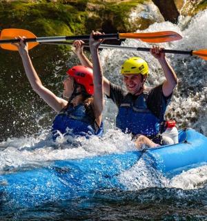 to personer er spær på en tømmerflåde i vandet