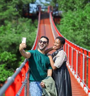 two men standing on a bridge taking a picture