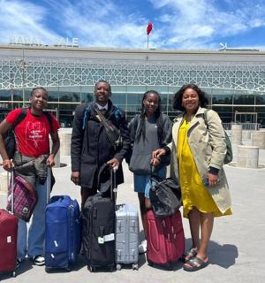 四个人带着行李站在机场前