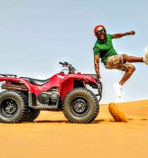 un bărbat sărind în aer lângă un camion în deșert