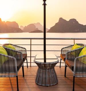 a balcony with chairs and a table with a view of the water