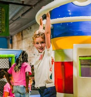 一个小女孩站在玩具水桶旁边