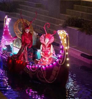 two women in costumes on a boat in the water at night