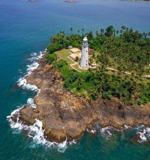 an aerial view of a lighthouse on an island in the ocean