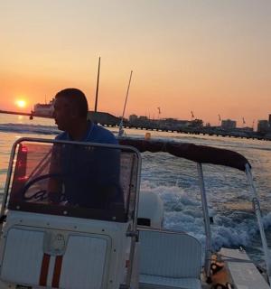 a man driving a boat in the water at sunset