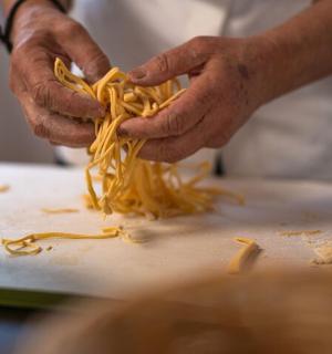 a person is preparing noodles on a cutting board
